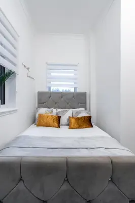 a large bed in a white bedroom with a large headboard at Coatbridge Apartment in Coatbridge