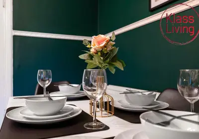 a table with plates and glasses and a vase with a rose at Alexander Apartment by Klass Living Coatbridge in Coatbridge
