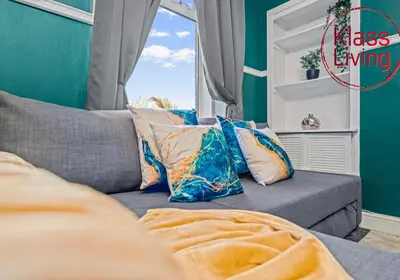 a couch with pillows sitting in front of a window at Alexander Apartment by Klass Living Coatbridge in Coatbridge