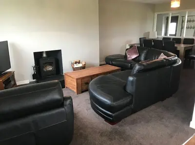 a living room with black leather furniture and a fireplace at Inishroel Cottage in Campbeltown