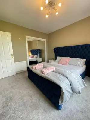 a bedroom with a blue bed with pink pillows on it at The Naburn - 3 Bed House with Free Parking & Close to City Centre in Glasgow