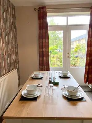 a wooden table with plates and glasses and a window at The Naburn - 3 Bed House with Free Parking & Close to City Centre in Glasgow