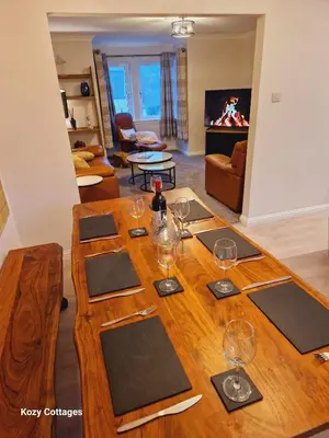 a wooden table with wine glasses on it in a living room at Ben Arthur Apartment in Lochgoilhead