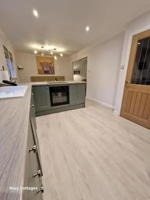 a large kitchen with a wooden floor and a door at Ben Arthur Apartment in Lochgoilhead
