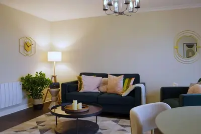 a living room with a blue couch and a table at Seaside Apartment in Largs
