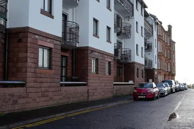 a red car parked on a street next to buildings at Seaside Apartment in Largs