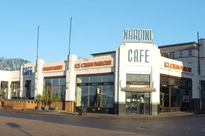 a white building with a cafe on the side of a street at Seaside Apartment in Largs