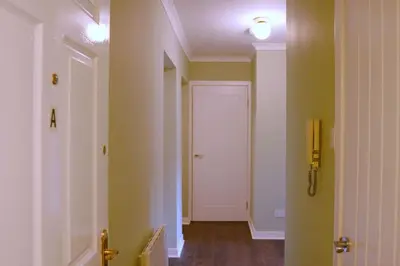 a hallway with a white door and a phone on the wall at Seaside Apartment in Largs