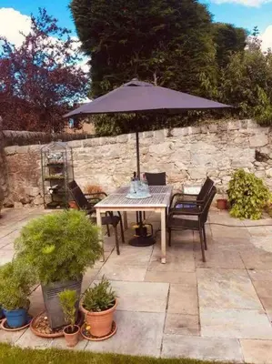 a picnic table with an umbrella in a garden at Wardie Garden Cottage in Edinburgh
