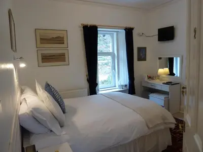 a bedroom with a white bed and a window at Failte Bed & Breakfast in Oban