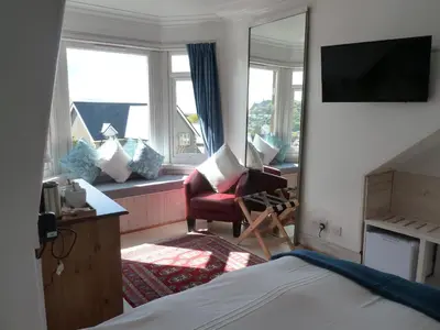 a hotel room with a bed and a chair and windows at Failte Bed & Breakfast in Oban