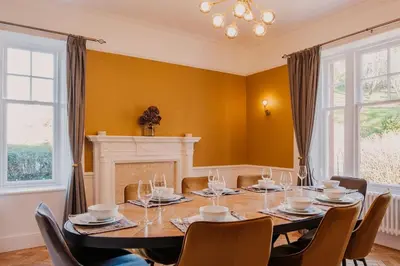 a dining room with a table and chairs and a fireplace at The Old School House, luxury home with hot tub. in Minnigaff