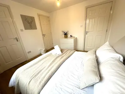 a bedroom with a large white bed with white sheets at Private room with en-suite and parking in shared flat in Glasgow