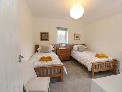 a bedroom with two beds and a chair at The Pier House in Lochgilphead