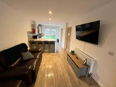 a living room with a brown leather couch and a kitchen at Inchmurrin Townhouse, Loch Lomond in Bonhill