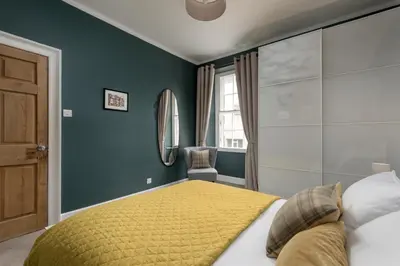 a bedroom with a large bed with a yellow blanket at Rose Apartment in Edinburgh