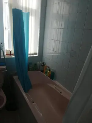 a bathroom with a tub with a blue shower curtain at Comfortable Rooms With Work Desks In Cheerful Apartment Glasgow City in Glasgow
