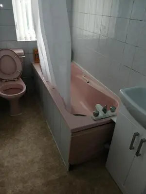a bathroom with a pink tub and a toilet at Comfortable Rooms With Work Desks In Cheerful Apartment Glasgow City in Glasgow