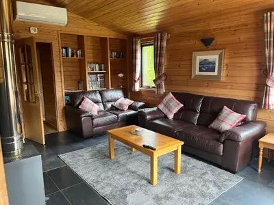 a living room with a leather couch and a coffee table at Loch Lomond Lodge in Rowardennan