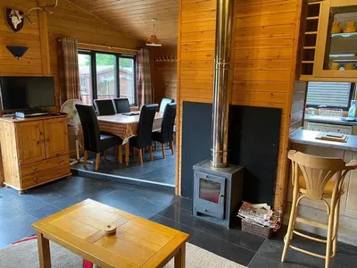 a living room with a wood stove and a table at Loch Lomond Lodge in Rowardennan