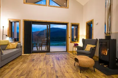 a living room with a couch and chairs and a fireplace at Luxury Cabins at Glenorchy Farm in Dalmally