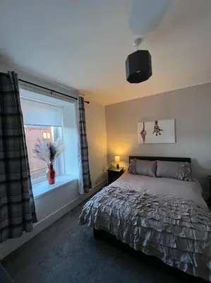 a bedroom with a bed and a window with a vase at Newly refurbished flat - Callander in Callander