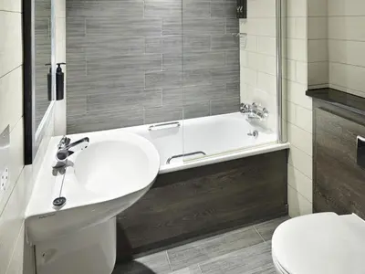a bathroom with a sink and a tub and a toilet at Village Hotel Edinburgh in Edinburgh