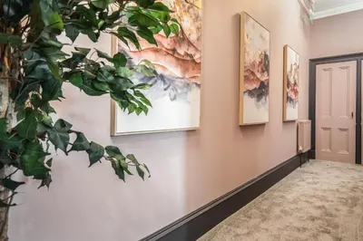 a hallway with paintings on the wall and a plant at Boutique Home Stay Blossom in Paisley