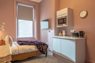 a small kitchen with a bed and a microwave at Boutique Home Stay Blossom in Paisley