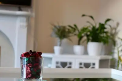 a glass vase with flowers in it on a table at Amazing 2-Bed Home w/ Private Garden Free Parking in Cardonald