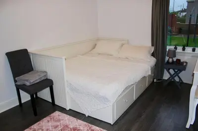 a bed in a room with a chair and a window at Amazing 2-Bed Home w/ Private Garden Free Parking in Cardonald