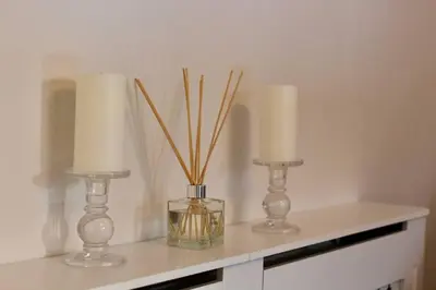 two candles and a vase with sticks in it on a table at Amazing 2-Bed Home w/ Private Garden Free Parking in Cardonald
