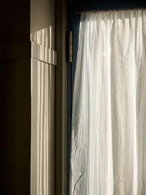 a window with a white curtain in a room at Jameswood Villa in Sandbank