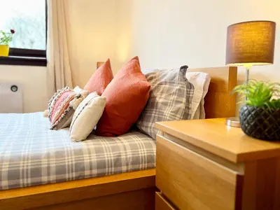 a bed with several pillows on it with a table at Beautiful & Spacious 2-Bed Flat in City Centre with Free Parking in Glasgow