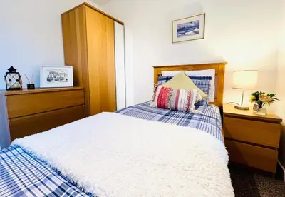 a bedroom with a bed with a wooden headboard at Beautiful & Spacious 2-Bed Flat in City Centre with Free Parking in Glasgow