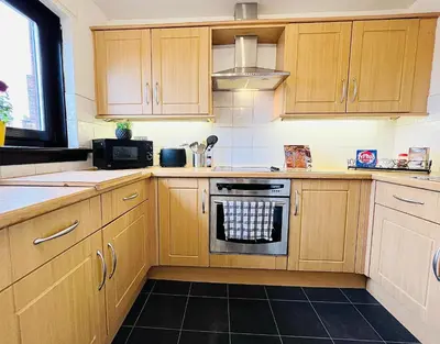 a kitchen with wooden cabinets and a stove top oven at Beautiful & Spacious 2-Bed Flat in City Centre with Free Parking in Glasgow