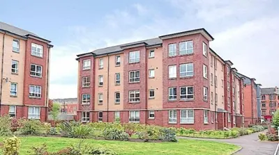 a large brick building with a grass yard in front of it at Spacious Modern Apartment in Glasgow