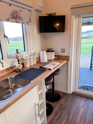 a kitchen with a desk with a sink and a window at Capledrae Farmstay Shepherds Huts in Cardenden