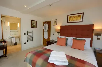 a bedroom with a large bed and a bathroom at The Lodge at Carrick Castle Estate in Cairndow