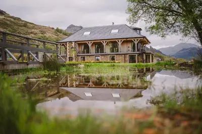 a house sitting on top of a body of water at The Lodge at Carrick Castle Estate in Cairndow