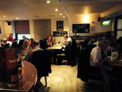 a group of people sitting at a table in a restaurant at The Pipers' Tryst Hotel in Glasgow