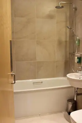 a bathroom with a shower and a tub and a sink at The Pipers' Tryst Hotel in Glasgow