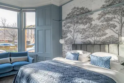 a blue bedroom with a bed and a couch at Bluebell Studio Glasgow Airport in Paisley