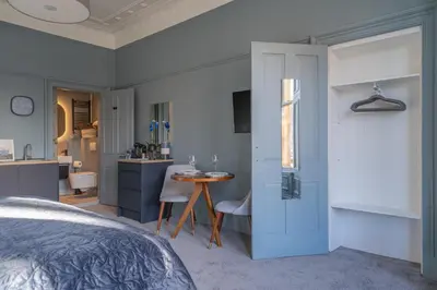 a bedroom with a bed and a table and a kitchen at Bluebell Studio Glasgow Airport in Paisley