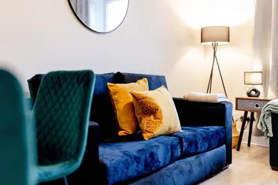 a blue couch with yellow pillows in a living room at Welcoming Home in Johnstone, Near Glasgow Airport - Bonnie Lodgings in Johnstone