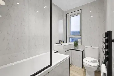 a white bathroom with a tub and a toilet at Welcoming Home in Johnstone, Near Glasgow Airport - Bonnie Lodgings in Johnstone