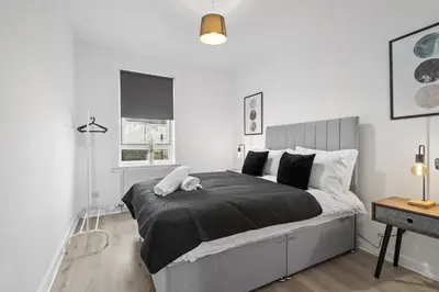 a bedroom with a large bed with a black comforter at Welcoming Home in Johnstone, Near Glasgow Airport - Bonnie Lodgings in Johnstone