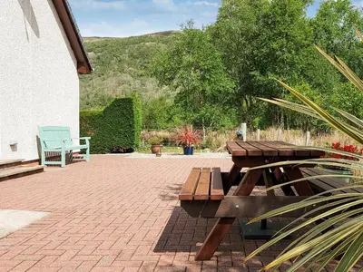 a picnic table and bench on a brick patio at Roe Deer Cottage in North Ballachulish