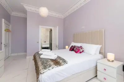a white bedroom with a large bed with towels on it at Spacious modern city centre apartment Castle Views in Edinburgh