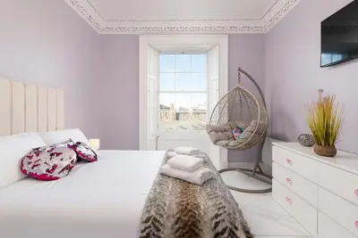 a bedroom with a bed and a chair and a window at Spacious modern city centre apartment Castle Views in Edinburgh